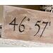 A personalized location sign. The lettering is wood-burned onto reclaimed wood by hand. The sign is finished with a whitewash. 